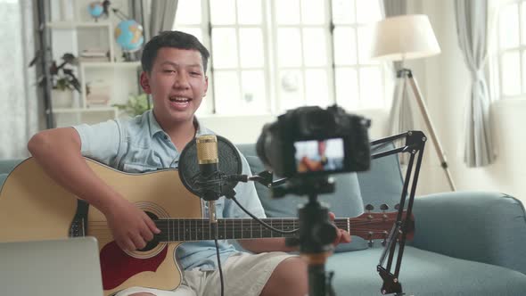 Asian Boy Is A Vlogger. Boy With Guitar Talking To Camera. The Boy Is Streaming