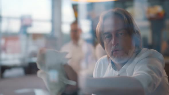 View Through Window of Mature Waiter in Apron Doing Daily Duties Indoors