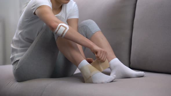 Female Applying Two-Strap Ankle Wrap, Suffering Foot Edema After Sport Trauma