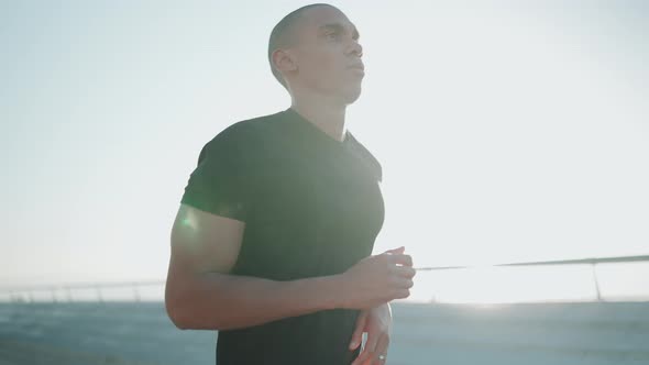 Concentrated bald sportsman wearing black t-shirt running outdoors