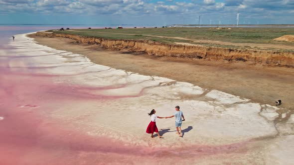 Lovely Young Couple Walking Along Beautiful Pink Lake with Salty Shore