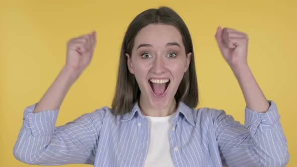 Young Woman Celebrating Success Isolated on Yellow Background