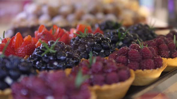 Horizontal Close Up of Fresh Berry Mini Tarts with Cream Filling in Bakery