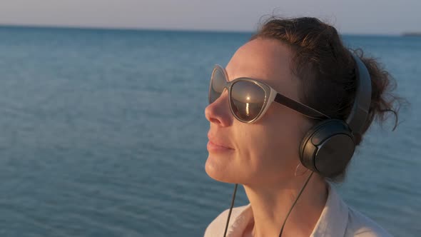 Woman in headphones meets the dawn. 