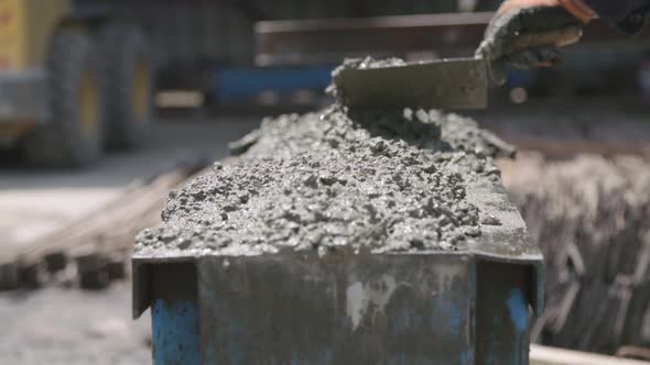 Workers pouring concrete into large steel molds on a construction site