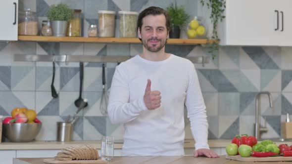 Young Man Showing Thumbs Up While Standing in Kitchen