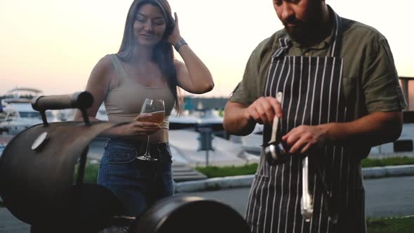 Happy Friends are preparing meat steak on grill.