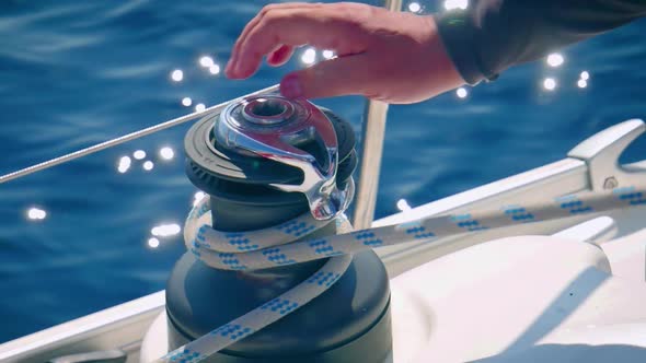 Hands Pulling And Rolling Rope On A Winch - Sailing Boat - close up