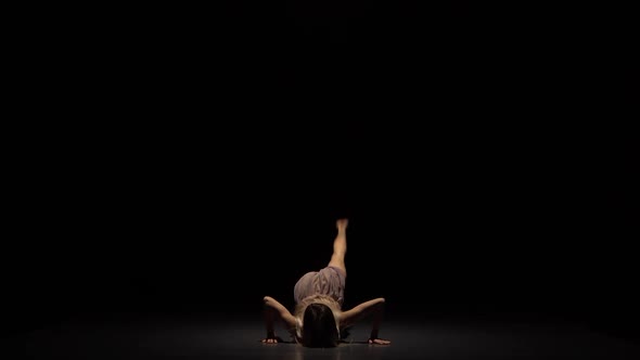 Graceful Girl Dancing and Sitting on Splits at Studio in Twilight.