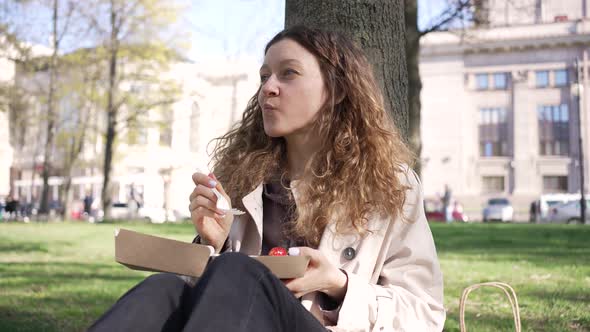 Woman Enjoys Delicious Cake with Fresh Fruits in City Park
