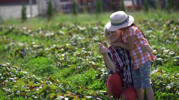 Mother with Her Little Daughter in the Allotment of Strawberries