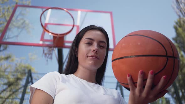 Portrait Adorable Teen Brunette Girl Holding a Basketball Ball Looking at the Camera Standing