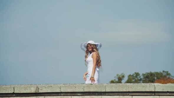 Girl in a White Dress with Hat Walking on the Walls of the Castle