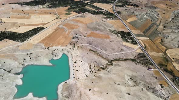 Drone filming of a small lake lost between hills and fields near a road in Turkey