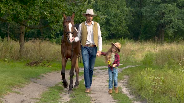 Cowboy with His Daughter Walking with a Horse on a Forest Road