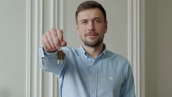 Man Shows the Keys to His New Apartment in the Living Room