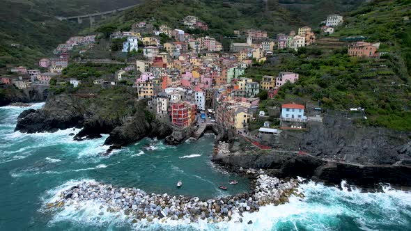 Cinque Terre Colorful village of Riomaggiore with waves crashing over breakwater