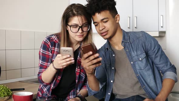 Attractive Guy and a Girl Both in Their 20's Scrolling Their Smartphones Exchanging Information