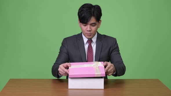 Young Asian Businessman Looking Happy and Surprised While Opening Gift Box