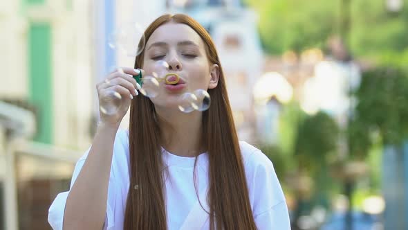 Attractive Young Female Blowing Soap Bubbles Smiling on Camera, Slow-Motion