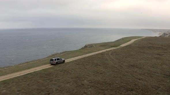 Aerial Side Tracking Shot High Speed Suv Automobile Driving on Top of Mountain Road Natural Sky