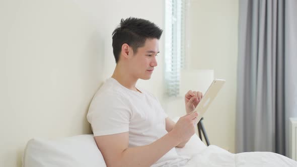Asian handsome man read online news from tablet in morning at home.