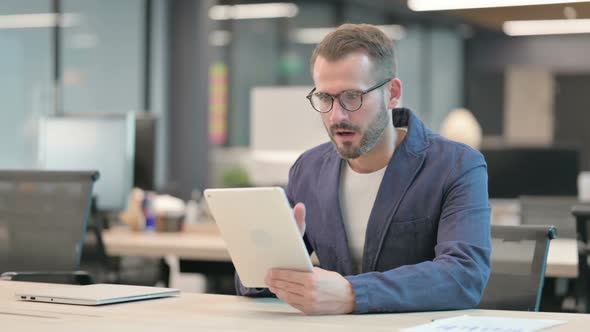 Middle Aged Businessman Reacting to Loss on Tablet While Sitting in Office