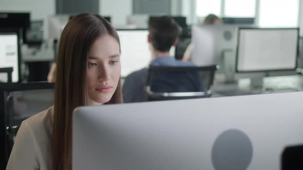 Attractive Young Woman Working on Decktop Computer While Working in Big Open Space Office