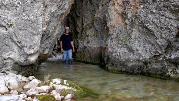 Young Man Walking Through Water Cave