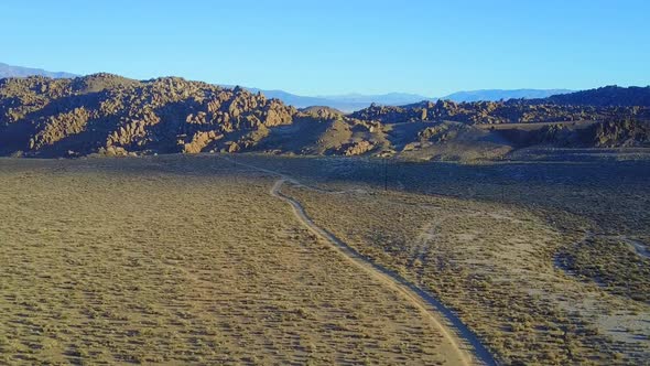 Scenic aerial drone view of dirt road and rocky desert landscape.