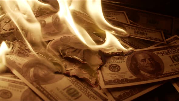 Pile of Hundred Dollar Bills Lie on Floor Against Dark Background and Slowly Burn Closeup