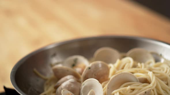 Camera follows cooking pasta with clams in a pan. Slow Motion.