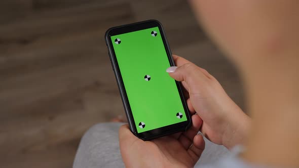 Closeup of a Woman Holding a Phone with a Green Screen at Home