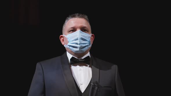 Man in elegant suit and medical mask. Portrait of an actor in protective facial mask 