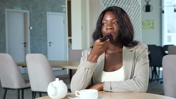 AfricanAmerican Woman Records Audio Message in Cafe