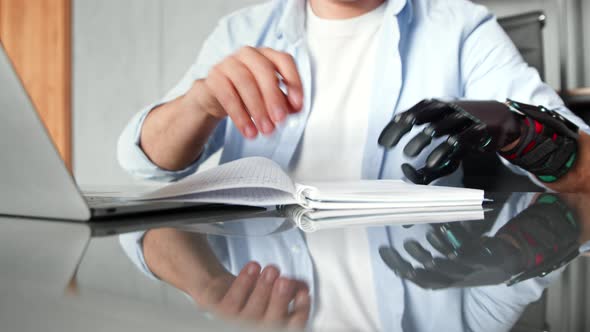 Disabled manager man with artificial bio hand prothesis makes notes in paper notebook