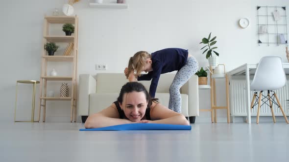 Little Girl Helps Mother Stretching Legs Indoors