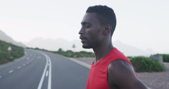 Portrait of african american man exercising on mountain road stopping to rest during run