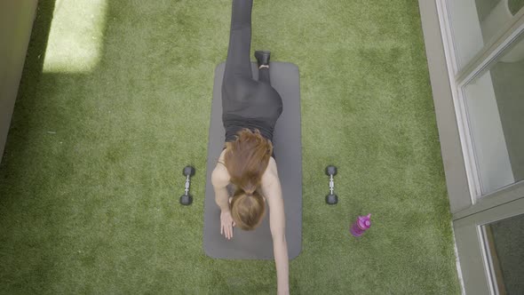 An aerial shot of a woman stretch posing in her back yard 4k60