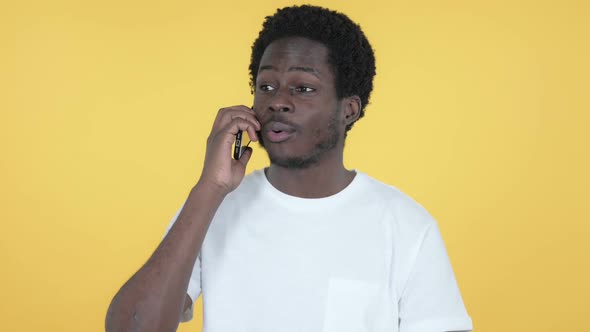 African Man Talking on Smartphone Yellow Background