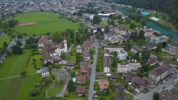 Aerial lowering on Catholic and Protestant Churches in Interlaken town valley next to lake, surround