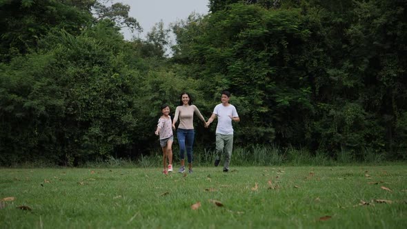 Slow motion of parents with daughter running enjoy in the park