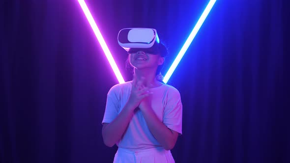 Excited Asian Young Girl Using Virtual Reality Headset And Feel Scary With Neon Light