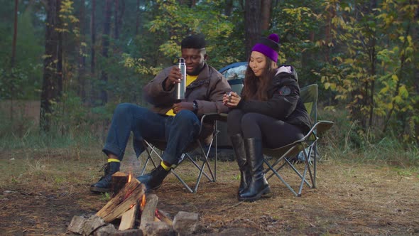 Tourists Near Campfire Warming Up with Hot Drink