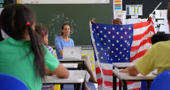 Front view of African american schoolboy explaining about American flag in the classroom 4k