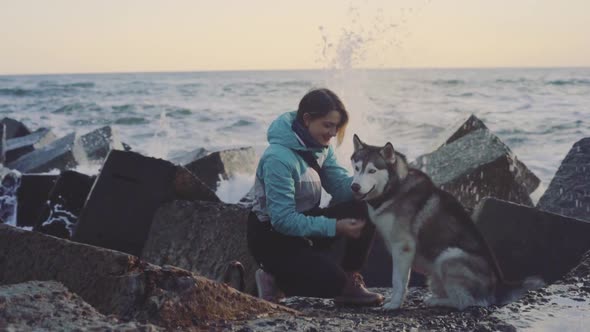 Young Beautiful Female Walking with Siberian Husky Dog on the Beach at Sunset Slow Motion