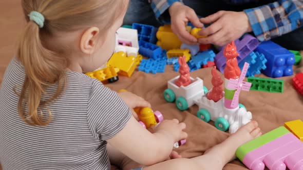 Dad and Daughter Play with Construction Set on Bed in Bedroom Indoors at Home