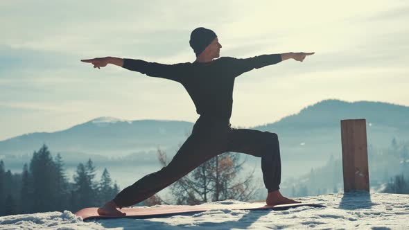 Caucasian Senior Man Doing Yoga Exercises in Front of Amazing Sunset on the Winter Mountains