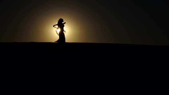 Girl Performs Beautiful Belly Dance on Sunset Background. Silhouette. Slow Motion