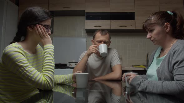 Family Discusses Problems Sitting in the Evening Sitting at a Table in the Kitchen Drinking Tea